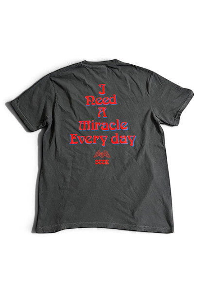 SEEKのDEGARASHIコラボTシャツ。背面に赤い文字で「I Need A Miracle Every day」とプリントされたヴィンテージ風の黒いコットンTシャツ